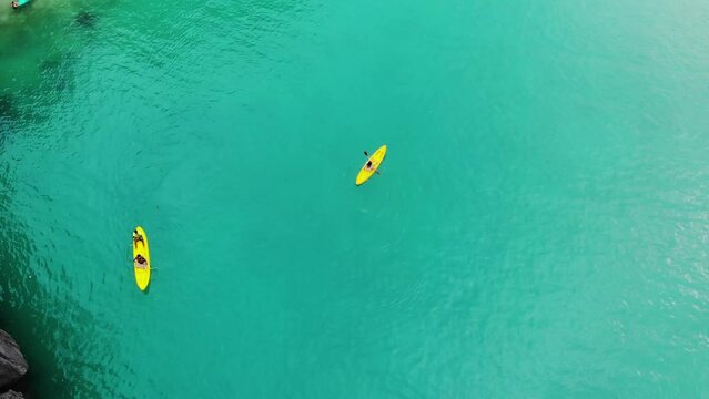 Girl paddles on a yellow kayak, aerial view