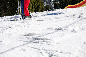Skiers stand before descending from a ski slope on a sunny day. Active family vacation
