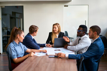Female CEO leads boardroom meeting with multiracial execs, discussing growth strategies. Team...