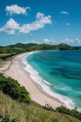 A panoramic view of a long, pristine beach stretching towards the horizon, flanked by lush green hills and crystal-clear turquoise water