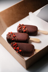 ice lolly with chocolate decorated with fruit in a cardboard box
