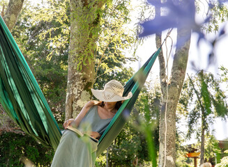 Woman reading in a hammock in the garden during a spring day.