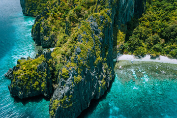 Aerial drone view of tropical island Entalula El Nido Palawan, Bacuit archipelago Philippines. Karst limestone rocky mountains surrounds blue bay with beautiful coral reef