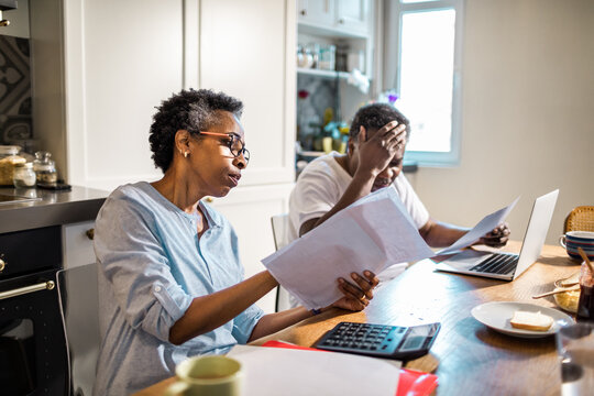 Concerned black senior couple with bills in the kitchen