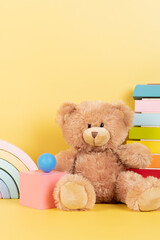 Educational kids toys collection. Teddy bear, wood rainbow, xylophone, wooden educational baby toys on yellow background. Front view