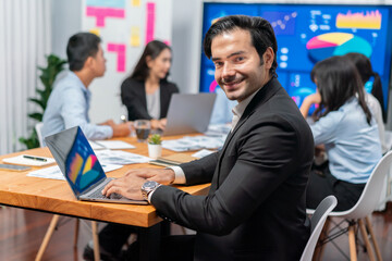 Portrait of businessman or analyst looking at camera with his colleague analyzing data analysis in dynamic business strategy investment planning meeting. Meticulous