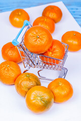 Fresh tasty tangerines in shopping cart on a table