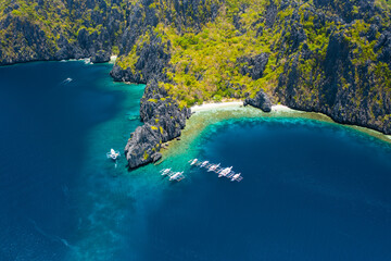 Aerial view of white boats in open sea close to tropical Miniloc Island. El Nido, Palawan island, Philippines