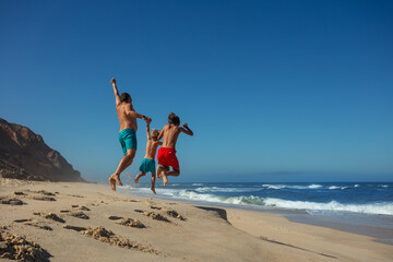 Three people, dad with kids boys enjoying ocean beach jumps - 784050923