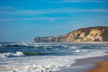 Fototapeta na wymiar Coastal scenery with gentle surfs meeting shore steep cliffs