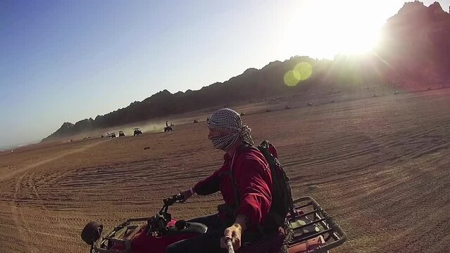 Riding on Quad Bikes in the Desert of Egypt. Driving ATVs. Adventures of desert off-road on ATVs. First-person view on action camera. Safari excursion.