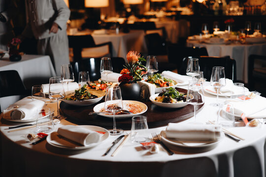 Beautifully organized event - round served table banquet ready for guests, round decorated table with empty plate, glasses, forks, napkin. Elegant dinner table 