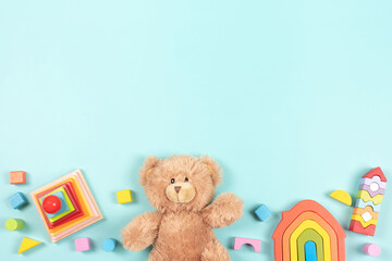 Baby kids toy frame background. Teddy bear, colorful wooden educational, sensory, sorting and stacking toys for children on light blue background. Top view, flat lay