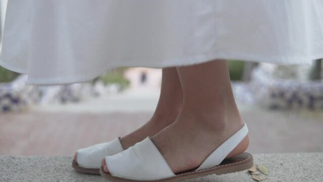 Closeup of white shoes on human feet on gray asphalt