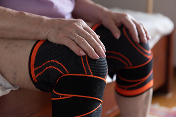 Old hands on knees, legs in knee pads, elderly man with sore arms and legs, arthritis and joint pain