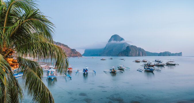 Panoramic scene of trip tourist boats in El Nido at evening sunset light. Palawan, Philippines. Cadlao island in background