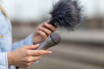 Reporter on the spot, holding microphone and dictaphone sound recorder in hand