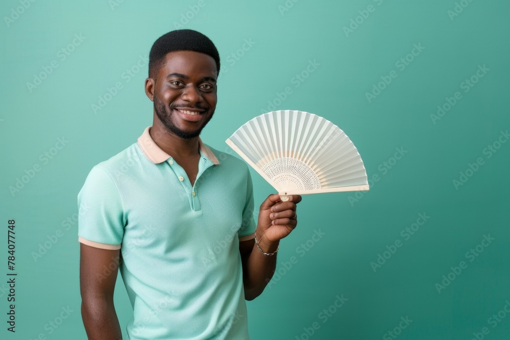 Wall mural A man is holding a fan and smiling. Summer heat concept - Wall murals