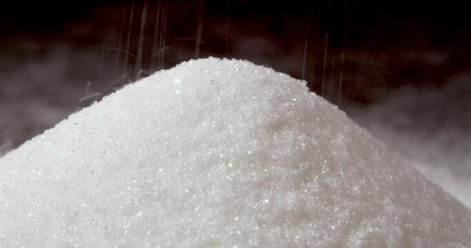 Sprinkling White Granulated Sugar into a Pile on a Grey Background