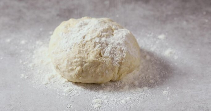 Sprinkling Flour onto a Pizza Dough Ball on a Surface