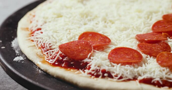 Topping Cheese PIzza with Pepperonis Before Baking