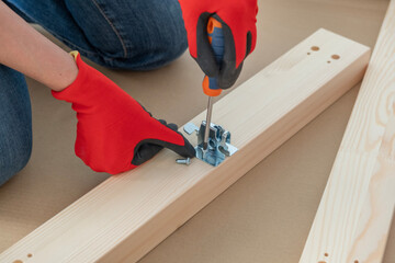 Woman hands assembling furniture at home. Woman using screwdriver while sitting on floor in apartment and assembling new table