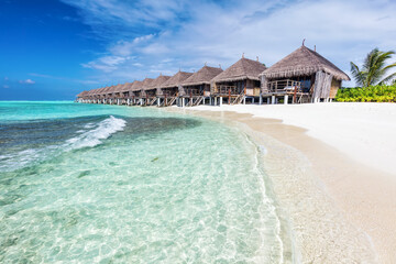 Water villas in a row by the seashore on Maldives Tropical resort