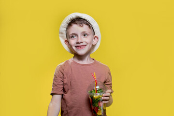 Cute little boy with inflatable ring and cocktail glass on yellow background