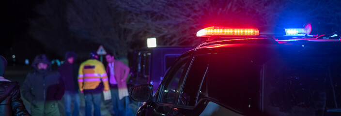 police officer stands next to a car he pulled over for speeding, reaching for the driver's ID,...