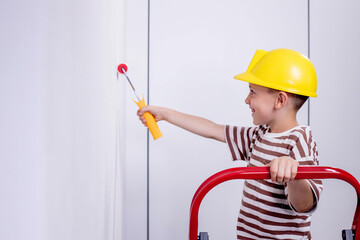 Cute boy with a paint roller. Happy kid helps parents to paint wall. New house for family.