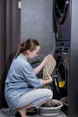 Young woman takes out the washed clothes from the washing machine at home