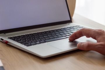 man's scrolling on laptop touch bar, close up black keyboard , silver modern laptop, blank white screen  