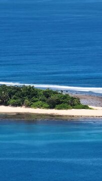 Zooming view of tropical island with white sand beach and waves. Mindanao, Philippines. Vertical, stories.