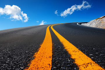 Naklejka premium Dramatic view of a curvy mountain road with vivid yellow stripes