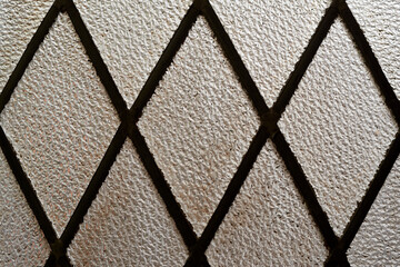 This image offers a detailed view of a textured glass panel, segmented by diamond-shaped metal...