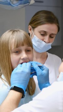Little girl getting teeth checked by dentist, hand in mouth