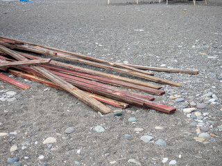 Old red boards on the sand. garbage. A mountain of wood. The building material is not suitable for use.