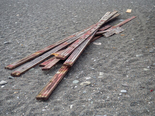Old red boards on the sand. garbage. A mountain of wood. The building material is not suitable for use.