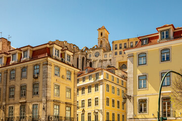 Fototapeta na wymiar Golden Yellow Buildings of Lisbon, Architecture Stepping up the Steep Hillsides, Portugal on a Sunny Spring Day