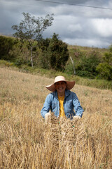 An adult woman happily working on her livestock farm with a hay bale in front of her on a sunny day