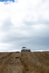 Naklejka premium Tractor with a hay baling machine on the horizon of a hill in the Andes mountains