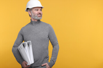 Architect in hard hat holding folders on orange background. Space for text