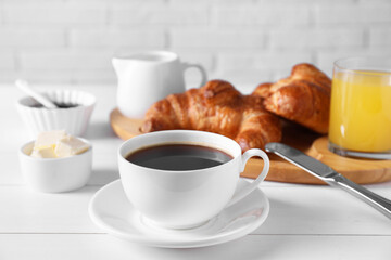 Fresh croissants, butter and coffee on white wooden table. Tasty breakfast