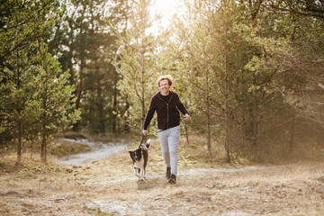 Mature man jogging in the forest with his border collie dog