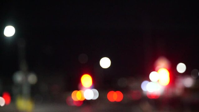 Blurred car lights bokeh in the evening city. Defocused headlights and street lighting at night. Moving bokeh circles of cars at night. Blurred city traffic background