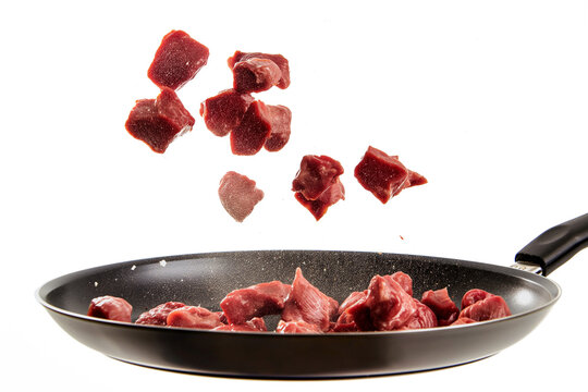 Pieces of meat flying in a frying pan on a transparent background