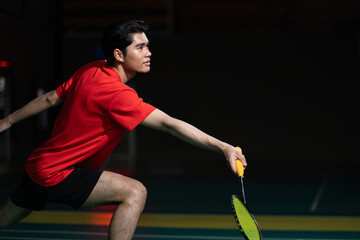Badminton player in a defensive position holding the racket. Wearing a red shirt in a badminton...