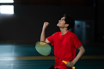 Badminton player side view celebrating victory, holding a racket, and cheering with overwhelming...
