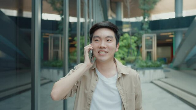 Handsome Asian student using smartphone. A young man walking outdoor happy smiling with talking with mobile phone
