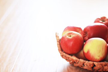 Wicker basket with fresh ripe red apples on wooden background. Harvesting. Autumn. September